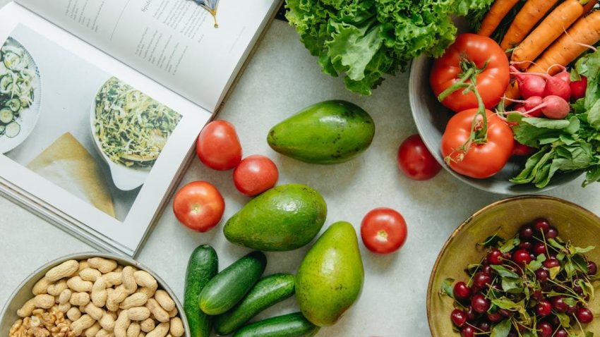 An appetizing display of fresh fruits and vegetables with a cookbook, perfect for healthy recipes.